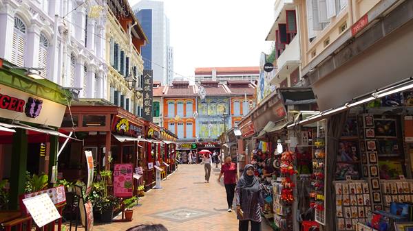 Shoppers walk past colorful shophouses and souvenir stalls in Singapore's Chinatown