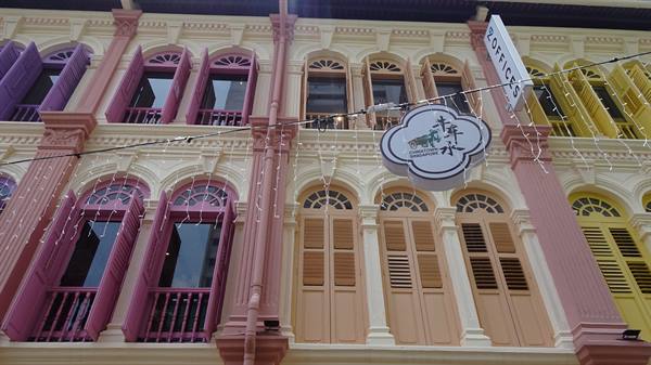 Colonial shophouse with pink, yellow and orange shutters, offices sign hanging outside