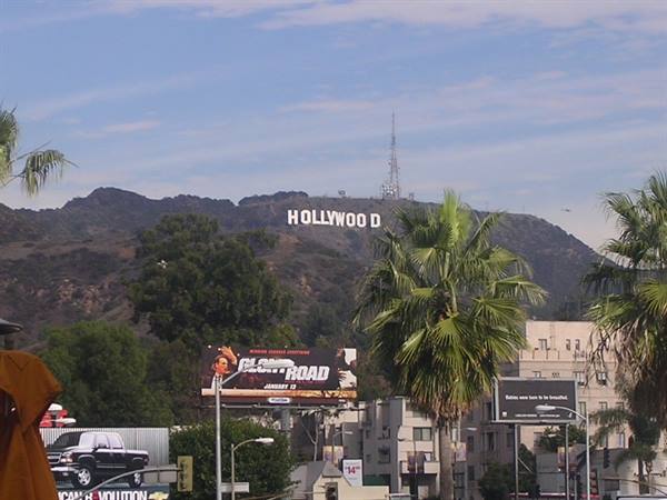 The Hollywood sign on Los Angeles hills among palm trees and billboards