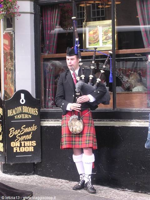 Bagpiper in tartan kilt playing outside Deacon Brodie's Tavern, Edinburgh