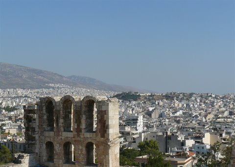 Ancient stone arches overlooking the white buildings of Athens