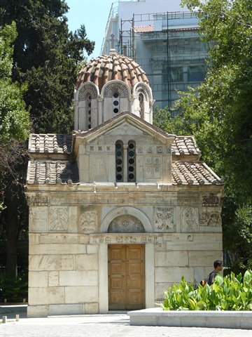 Small Byzantine marble chapel with tiled dome, nestled among green trees