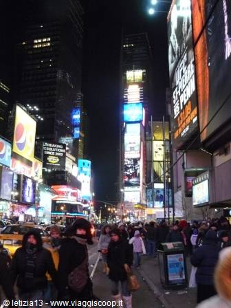 Crowd among taxis and glowing billboards in Times Square at night