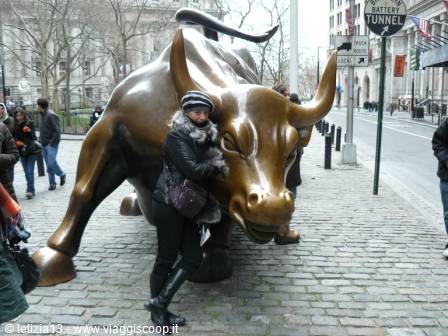 Tourist hugging the bronze Charging Bull statue on Wall Street, Manhattan