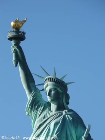 The Statue of Liberty holding her golden torch against a blue sky