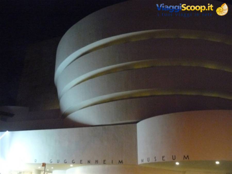 The curved concrete facade of the Guggenheim Museum illuminated at night in New York