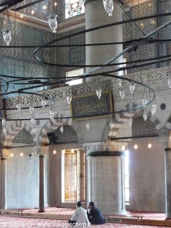 Hanging lamps and column inside the Blue Mosque, two visitors seated