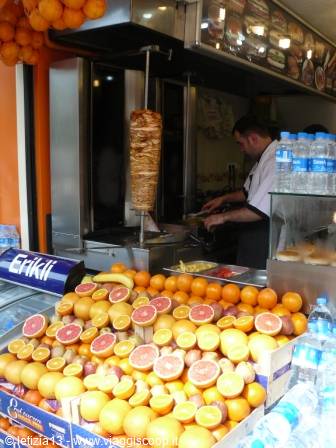 Cook slicing kebab from the spit at the stall, oranges and grapefruits in front