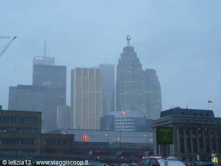 Toronto skyscrapers shrouded in fog, lights on, traffic in foreground