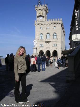 Smiling tourist in front of San Marino's Public Palace under sunny sky