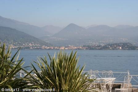 Lake Maggiore: wrought-iron tables among palms, Stresa and hazy mountains