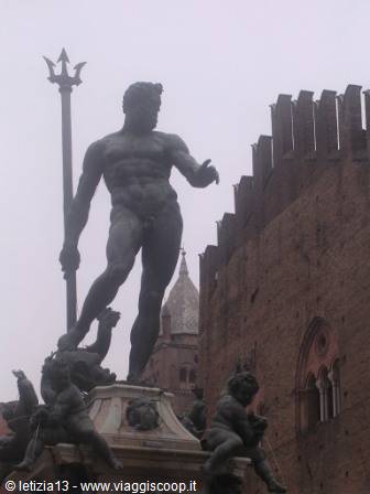 Bronze Neptune statue holding a trident, fountain in Bologna under grey sky