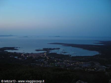 Coastal town lights at dusk among coves and blue islets