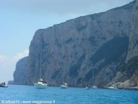 Sailboats anchored on turquoise sea beneath limestone cliffs