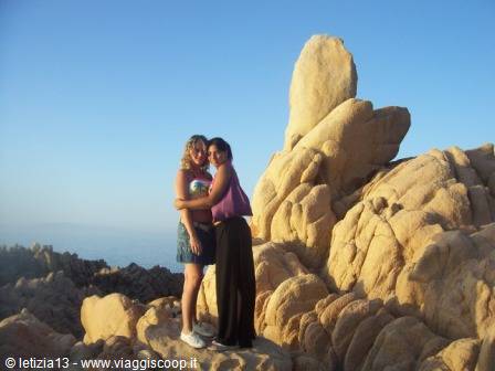 Two girls hugging on golden granite rocks above the sea