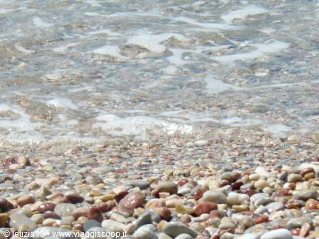 Foamy waves washing over a colorful pebble beach