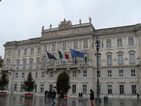 Government Palace on Piazza Unità d'Italia in Trieste, flags waving under grey sky