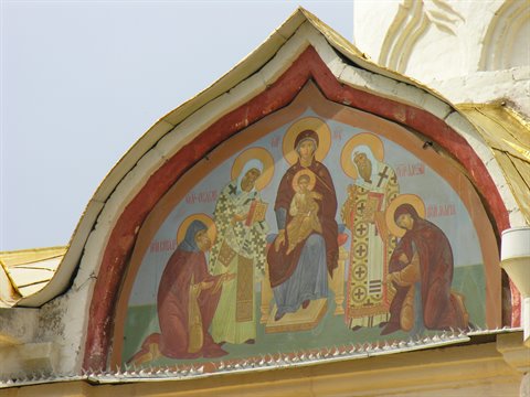 Religious fresco under an Orthodox church pediment, pale sky