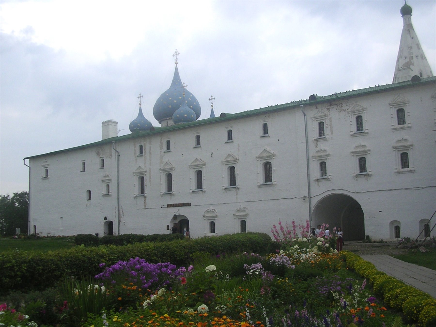 Mura bianche del cremlino di Rostov con cupole a cipolla blu sotto cielo nuvoloso