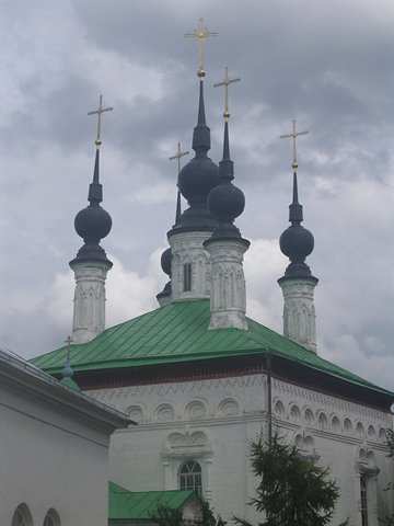 White church with green roof and five black onion domes topped by golden crosses