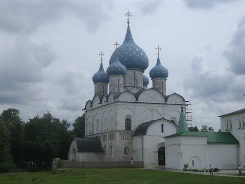 Nativity Cathedral in Suzdal, blue star-painted domes, white walls, cloudy sky