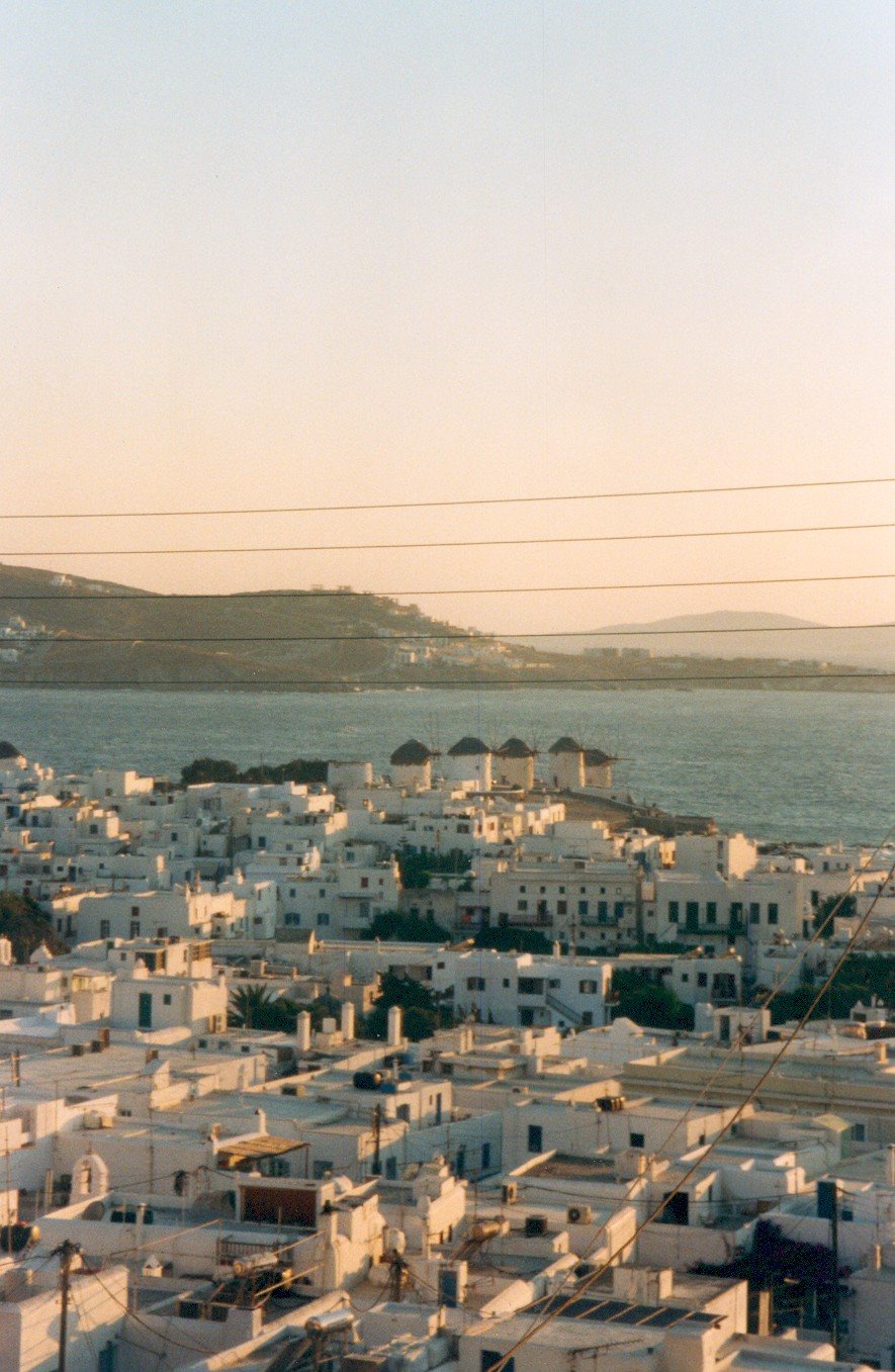 Tetti bianchi di Mykonos e mulini sul mare, luce dorata