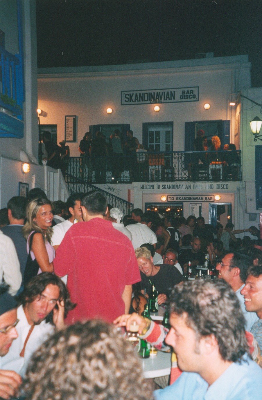 Folla di giovani in un bar affollato di notte, insegna Skandinavian Bar