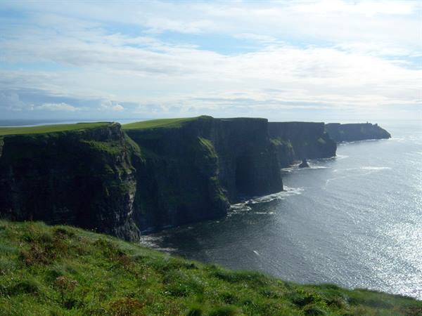 Cliffs of Moher: green cliffs plunging into the ocean under a cloudy sky