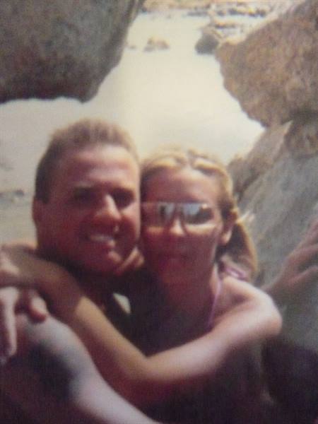 Smiling couple hugging among rocks and sea water