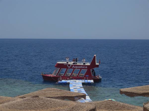 Red Aquatica semi-submarine boat moored at floating pier over turquoise water