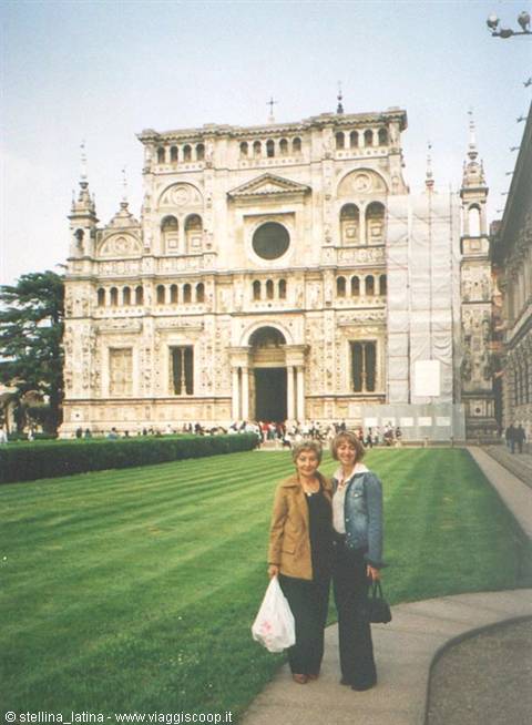 Two women posing on the lawn in front of the marble facade of Certosa di Pavia