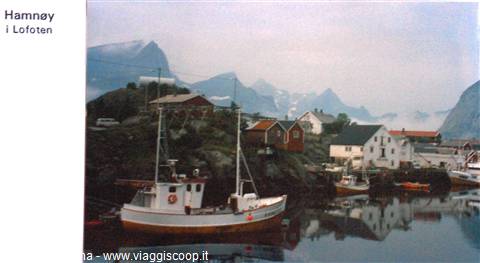 Fishing boats moored at Hamnøy harbor, wooden houses among snowy mountains