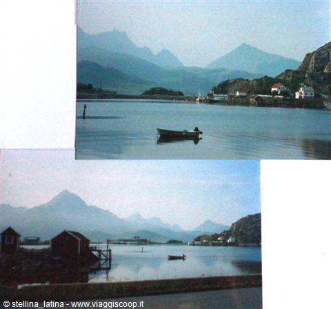 Wooden boat resting on calm water in front of snowy mountains and houses
