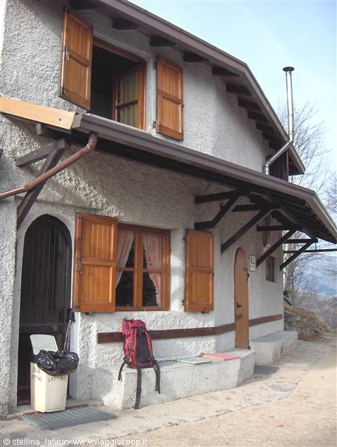 Red backpack on the bench outside a stone house with wooden shutters