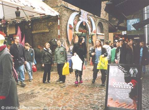 Visitors carrying plastic bags stroll through the stalls of Camden Market