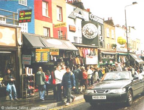 Crowd walking past colorful Camden Town shops, black car parked on the street