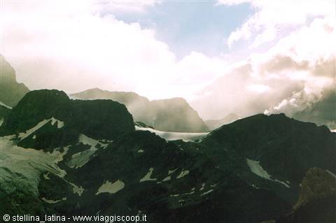 Glacier among dark rocky walls, mist and low clouds