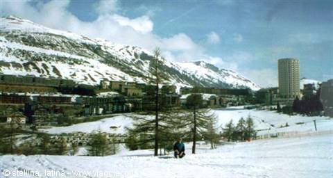 Skier on the snow in Sestriere, buildings and snowy mountains behind