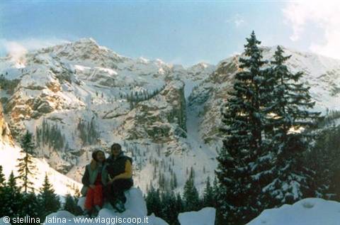 Couple on snow before snowy peaks and fir trees, winter light