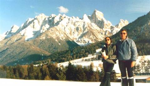 Couple in winter clothes in front of snowy Dolomites peaks