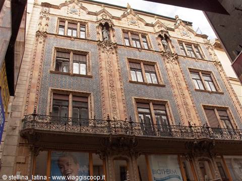 Art Nouveau building with blue ceramic tiles and statues between windows in Budapest