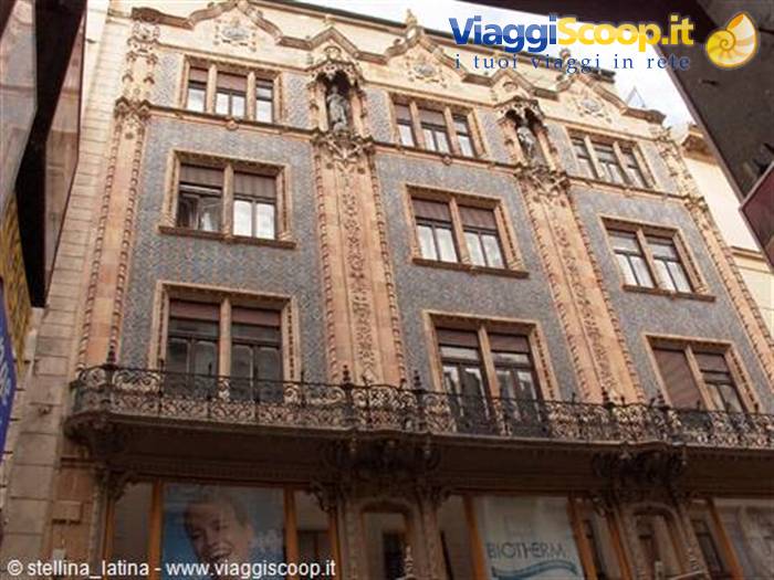 Art Nouveau building with blue ceramic tiles and statues between windows in Budapest