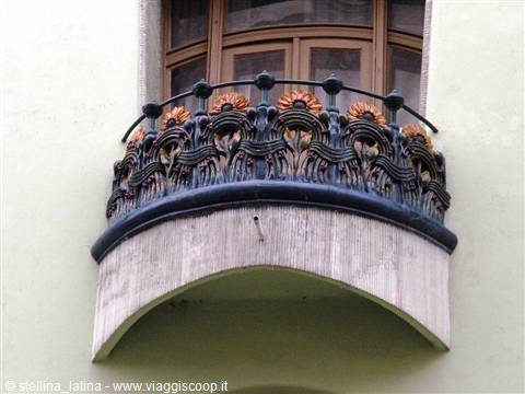 Art Nouveau wrought iron balcony with floral motifs under wooden window