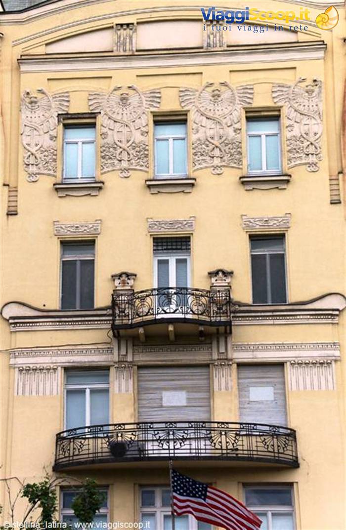 Art Nouveau yellow facade with carved owl reliefs and wrought-iron balconies