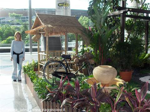 Woman beside a thatched hut and bicycle display at Singapore Changi airport