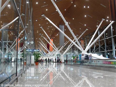 Kuala Lumpur airport: white Y-shaped pillars and wooden ceiling, travelers in the hall