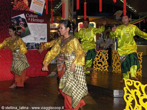 Dancers in yellow and green traditional costumes perform at a culture pavilion