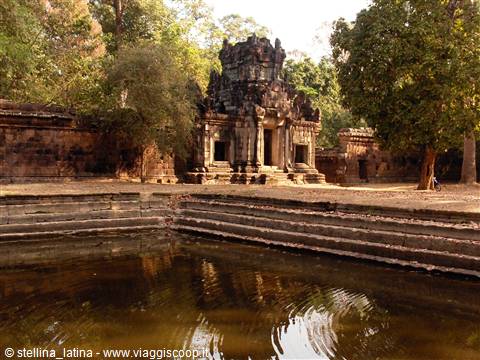 stone Khmer-style temple reflected in a pond surrounded by trees