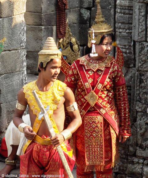 Dancers in gold and red costumes among Angkor temple stone walls