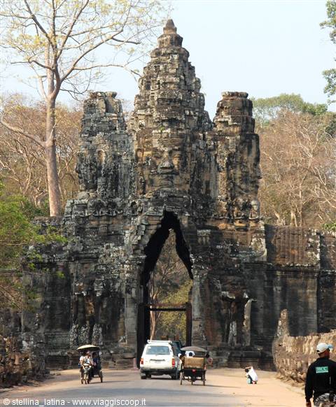 South gate of Angkor Thom, carved stone faces, cars and tuk-tuks passing beneath